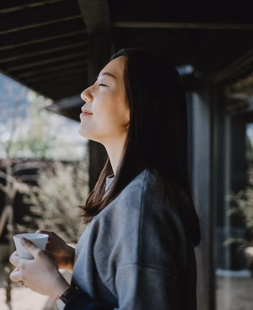 A woman reflecting over a cup of coffee